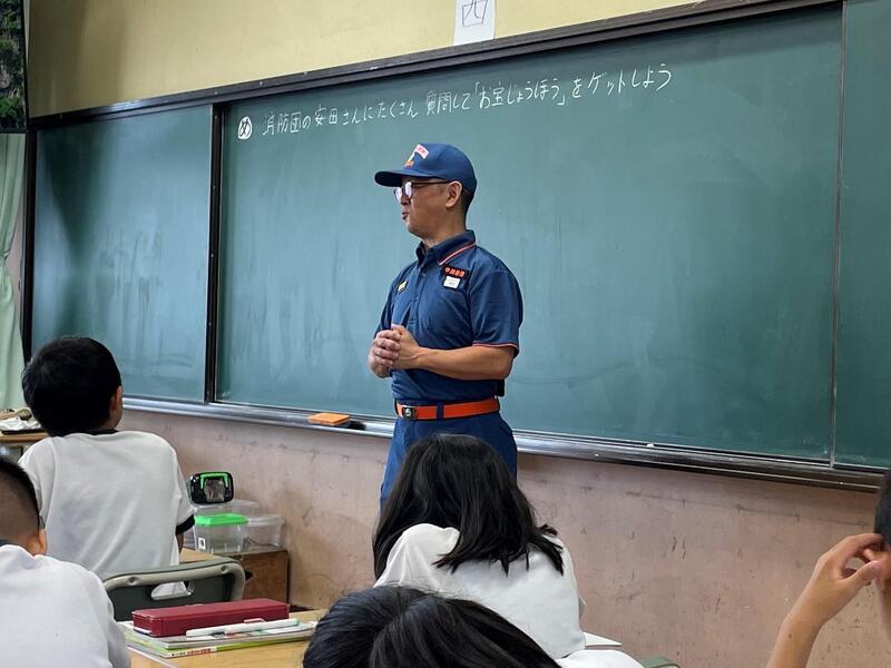 小学生に消防団のことを教えている消防団員