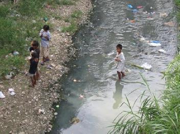 汚水が流れる川で遊ぶ子供達の画像