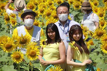 ひまわり畑の中の大塚会長と向日葵プリンセスの2人、区長の写真