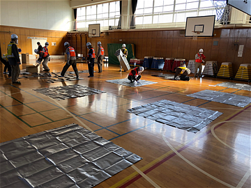 体育館にシートを並べている写真