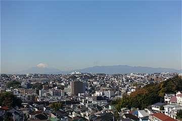 眼下に町並み、遠くに山並みと富士山の写真