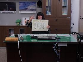 子ども委員が区長席に座って証書を持っている写真